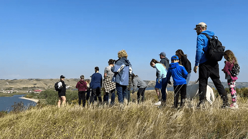 Park visitors attend an outdoor guided hike on a fall day overlooking a lake. 